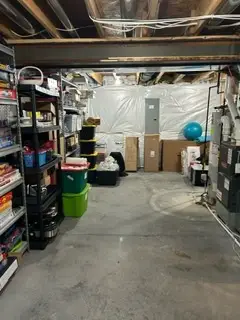 After — a clear concrete floor with bins lined along the back wall and games back on the shelving, basement in Union, KY