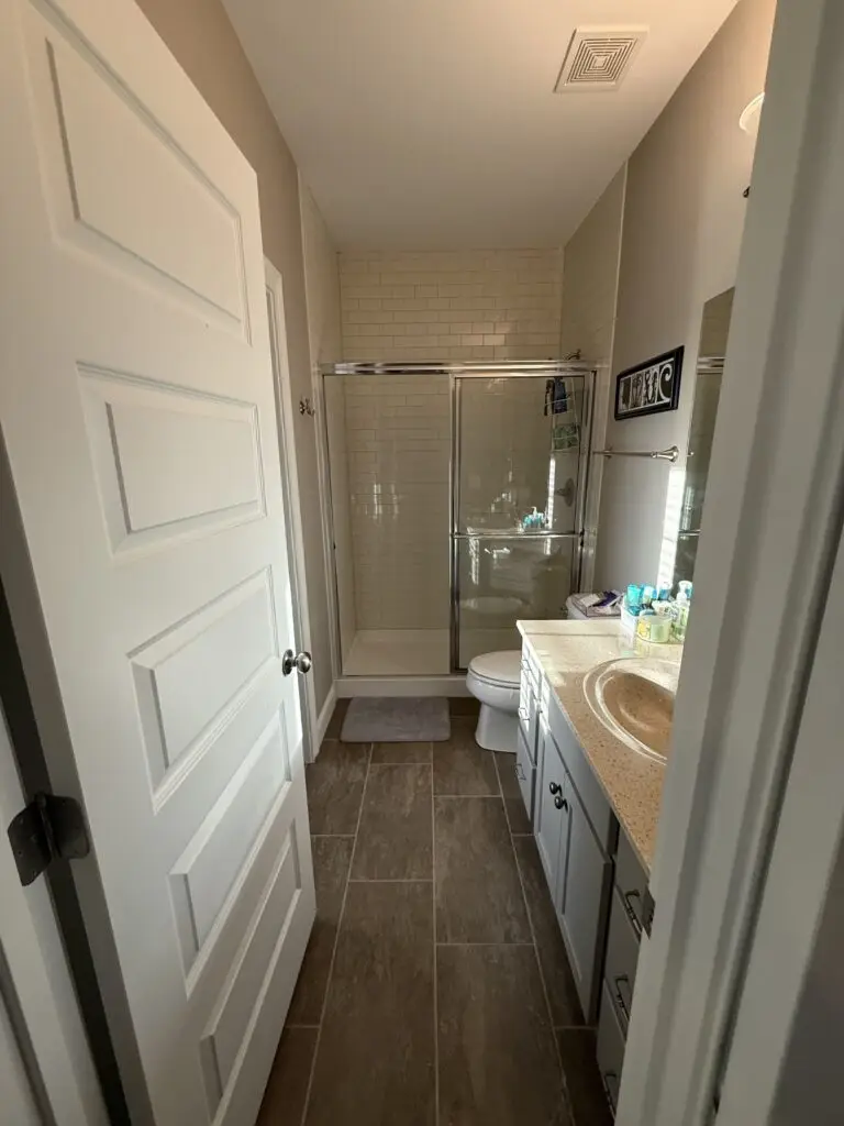 After — an empty shower with clean glass doors, a bath mat and a tidy counter, guest bathroom in Union, KY