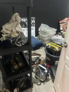 Before — shoes, tote bags, bins and a carpet cleaner spread across the floor beside a shelving unit, catch-all room in Union, KY