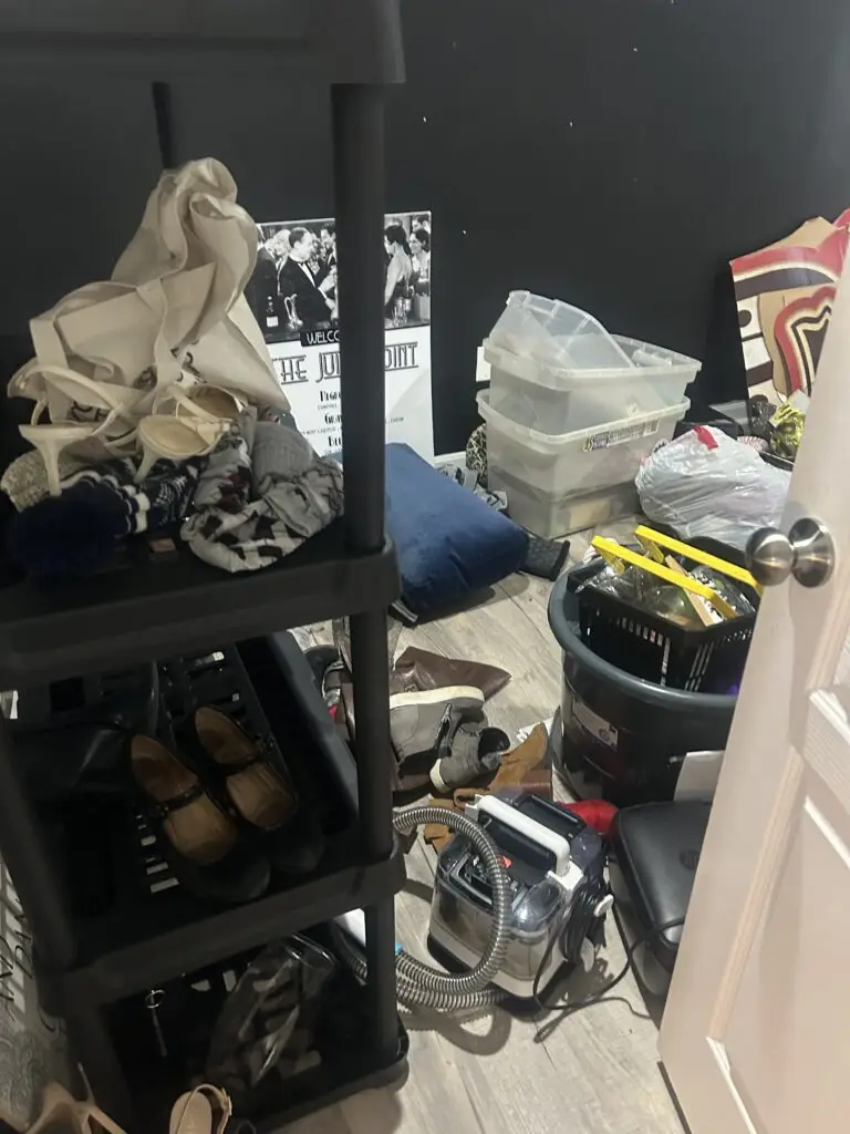 Before — shoes, tote bags, bins and a carpet cleaner spread across the floor beside a shelving unit, catch-all room in Union, KY