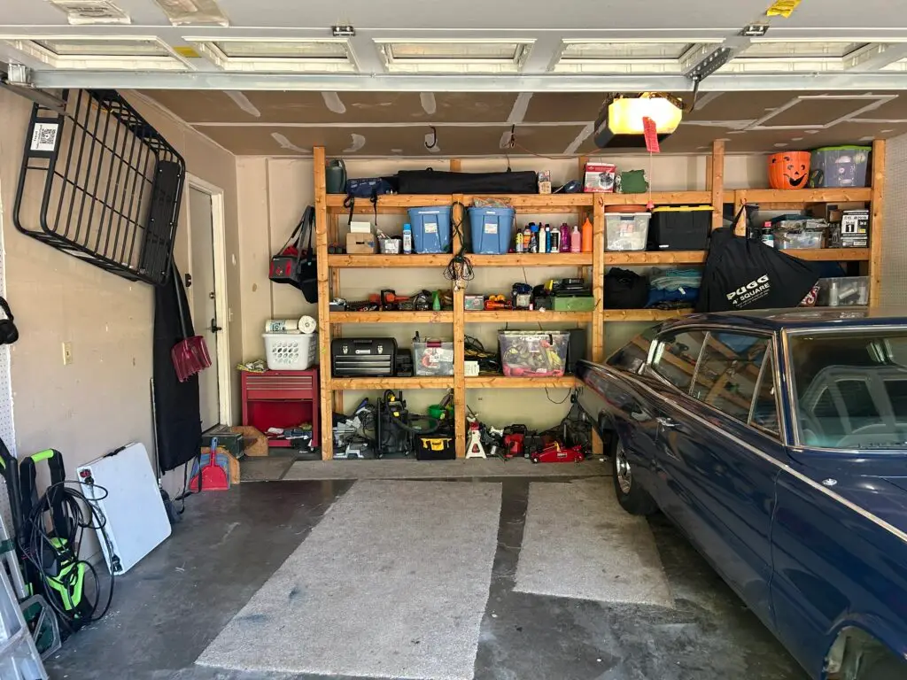 After — wooden shelving with lidded bins, toolboxes in a row and jacks lined up underneath, a clear floor beside the classic car, garage in Crescent Springs, KY