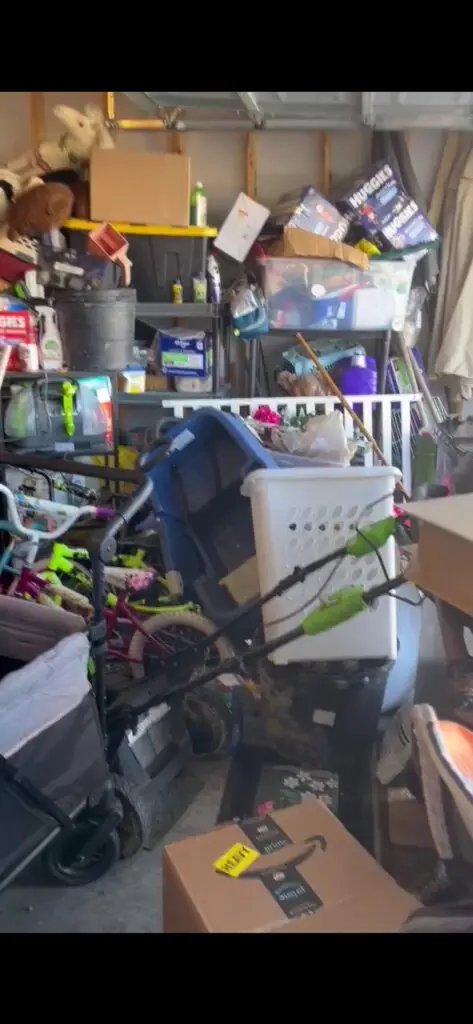 Before — a stroller, kids’ bikes, a laundry basket and stacked boxes blocking the walkway, garage in Loveland, OH