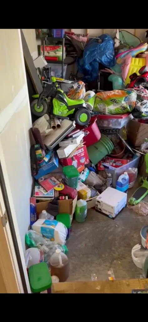 Before — a ride-on toy, diaper boxes, car fluids and loose bottles spread across the floor, garage in Loveland, OH
