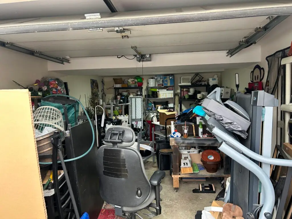 Before — an office chair, a treadmill and an elliptical parked in front of shelving with no path to the back wall, garage in Park Hills, KY