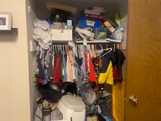 Before — a rail packed end to end with a shelf of boxes above and a hamper on the floor, kids closet in Cincinnati, OH