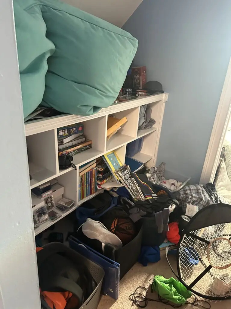 Before — cushions piled on top of an alcove cubby unit with a basketball, a sports net and a hamper on the floor, kids bedroom in Alexandria, KY