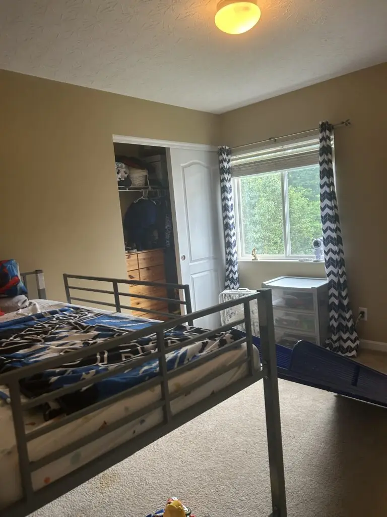 After — a clear carpet, a made bed and a cart of clear drawers beside the window, boys bedroom in Walton, KY