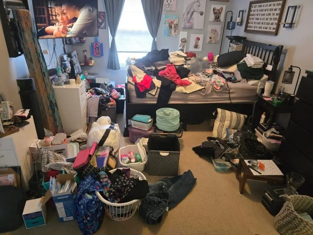 Before — clothes heaped on the bed with laundry baskets, bins and boxes covering the carpet, master bedroom in Park Hills, KY