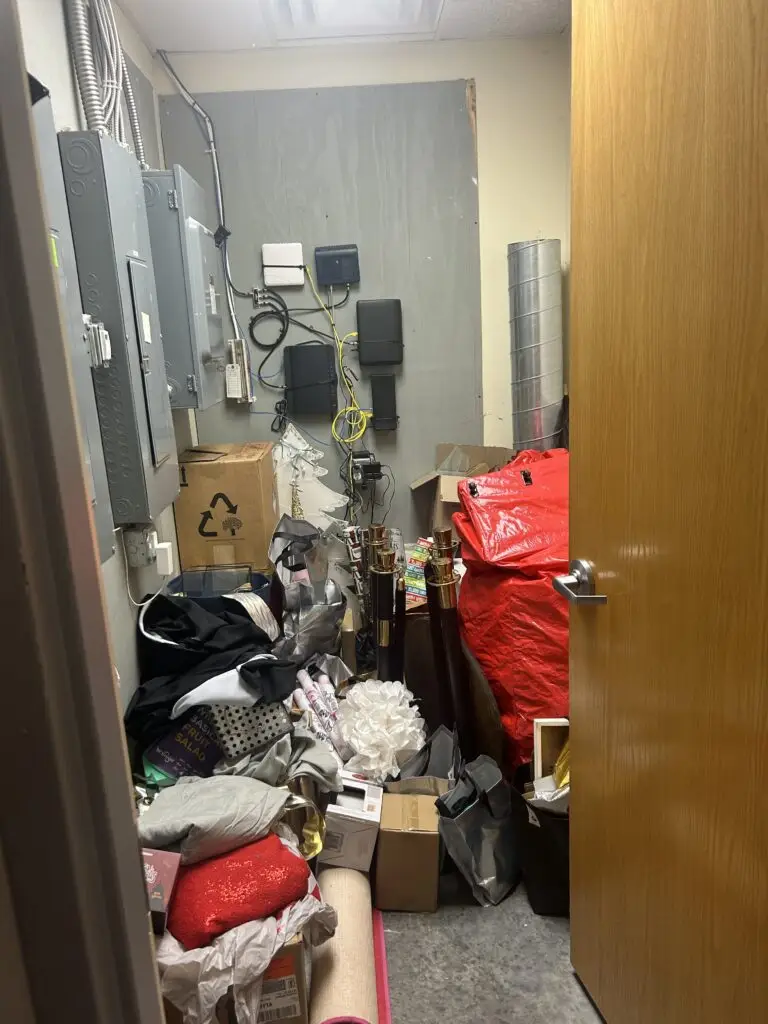 Before — rope stands, red bags, decorations and boxes filling the floor of a utility closet, med spa storage closet in Crescent Springs, KY