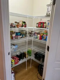 After — food grouped by type with open space on each shelf and a clear wood floor, corner pantry in Union, KY