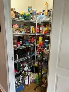 Before — every wire shelf packed to the edge with bags and bottles covering the floor, corner pantry in Union, KY